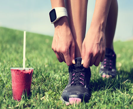 A runner with a fitness tracker and orange trainers rests by the river