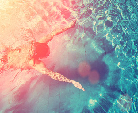A swimmer in a blue pool with lens flare