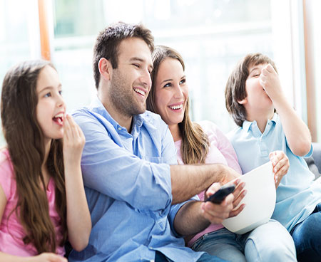 Family eating popcorn in front of TV