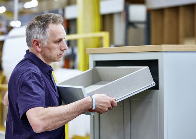 Man assembling chest of drawers in factory.