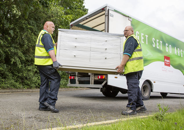 Delivery men carrying ready assembled bedroom furniture.