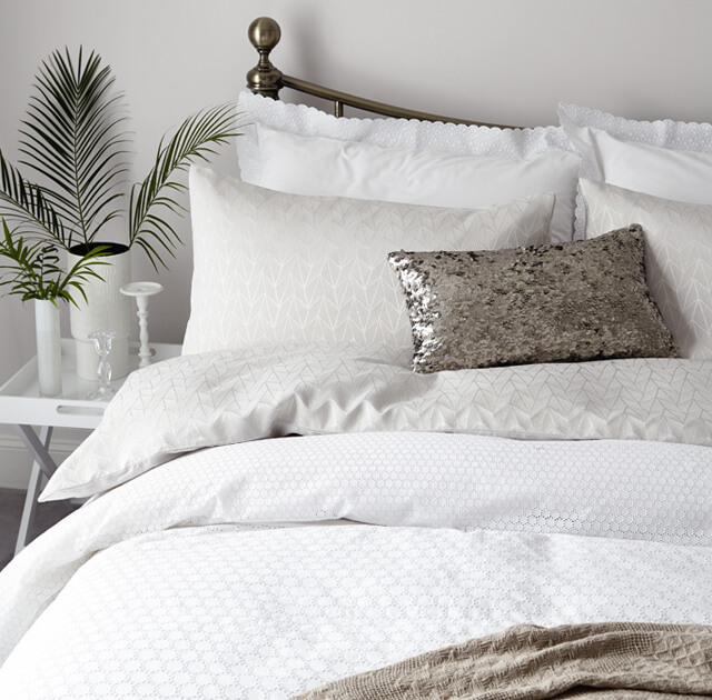 Cream leather bed layered with white jacquard bedding.