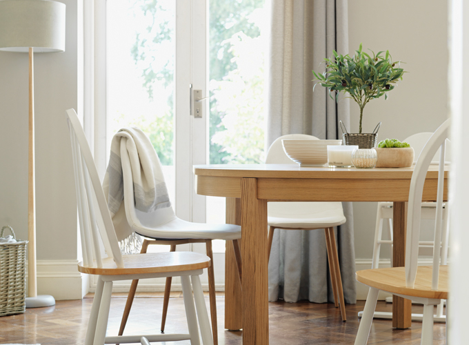 An oak-veneer dining table has a collection of white and wood-finish chairs.