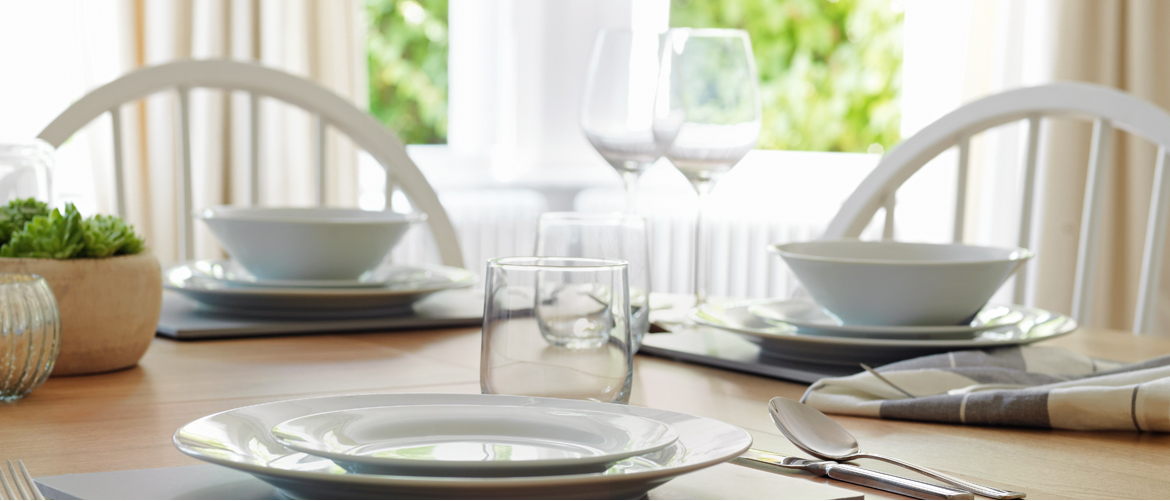 A table is set with white fine crockery and elegant glassware.