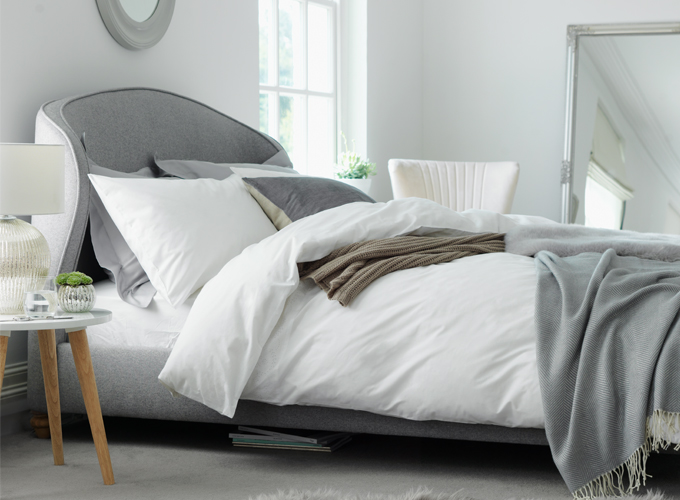 White and grey bedroom with fresh linen and grey bed frame.