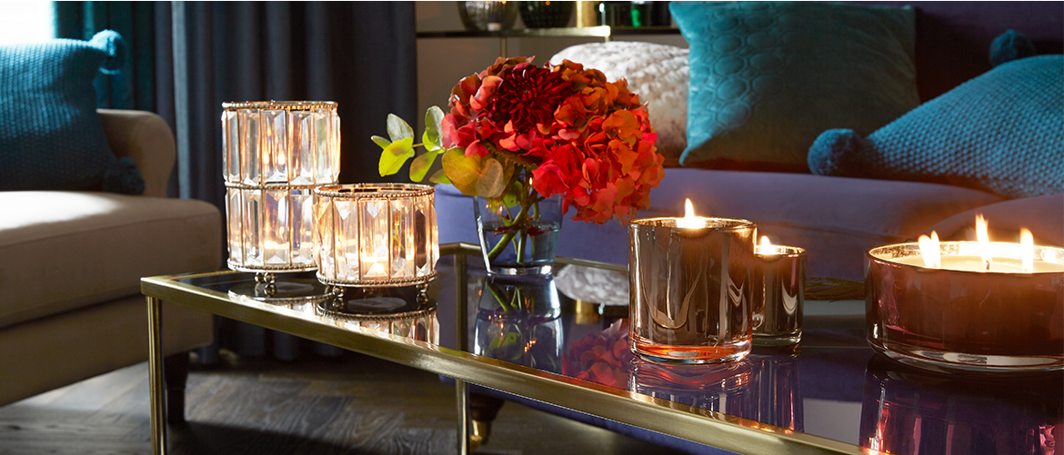 Image of a coffee table in the centre of a lounge, filled with lit candles and flowers.