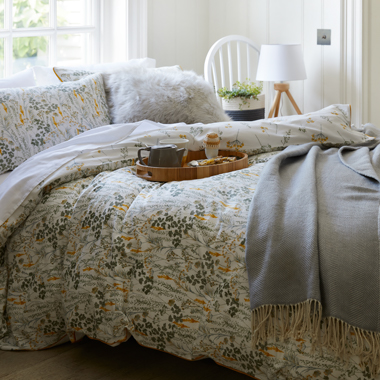 An image of a forest green and mustard yellow print wildflower bedding set with mustard piping around the edge.