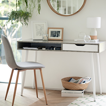 A concrete-effect desk used as a sidetable in a white-walled room.