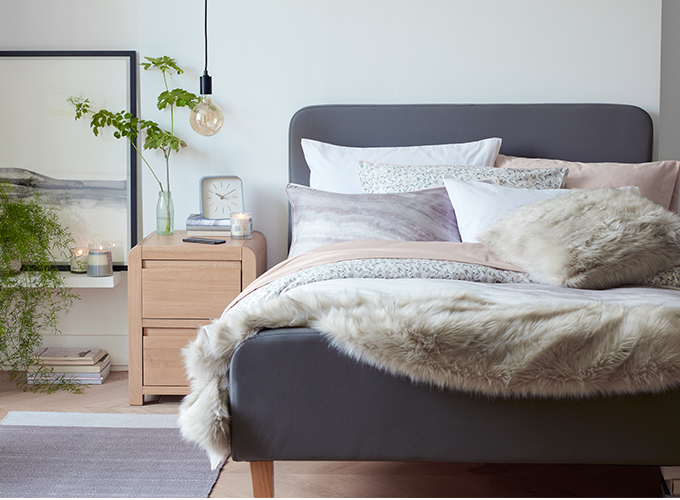 A Scandi-inspired bedroom with grey and blush coloured bedding and faux fur accessories.