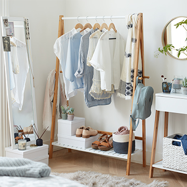 A wooden and white clothes rail layerd with white and blue clothes and accessories.