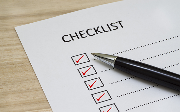 Checklist box with paper and a pen on wooden table