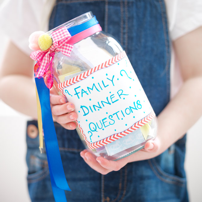 Image of a child holding a plastic jar with 'Dinner time questions' on the label.