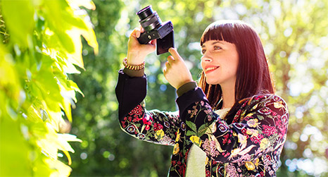 Image of a woman taking a scenic picture with a Canon DSLR camera.