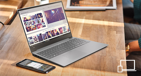 Image of a Windows laptop on a wooden desk with a mobile phone next to it.