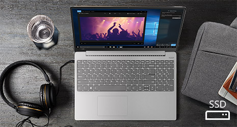Image of a Windows laptop on a desk with headphones plugged into it and a glass of water next to it.