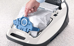 Lifestyle image of a dustbag being removed from a Miele vacuum cleaner.