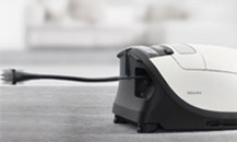 Sideon image of the back end of a white Meili vacuum cleaner with the power cord extending out of the cleaner.