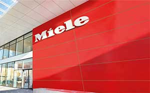 Image of a Miele branded building with a Miele logo on a red wall and glass exterior to the left.