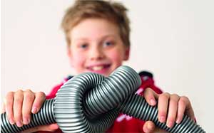 Image of a child tying the hose from a vacuum cleaner into a knot.