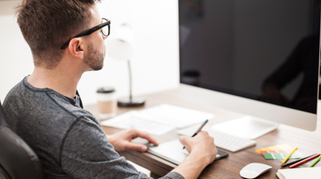 Man sat at a desk, looking at PC monitor