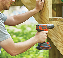 Image of a man using a drill driver to drill through wood.