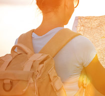 Image of a woman looking at a map and wearing a backpack.