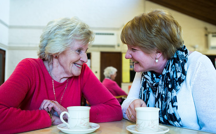 Elderly woman enjoying conversation and a cup of tea with a dementia friend