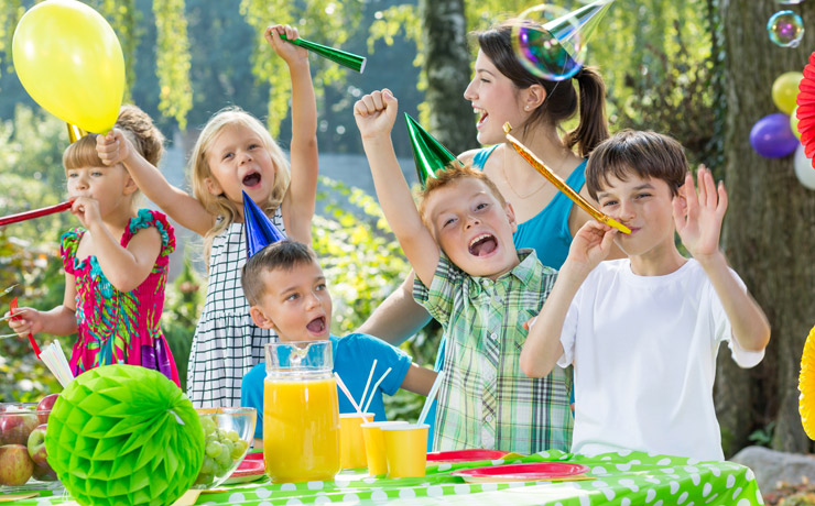 Children with party hats and bubbles at a garden party.