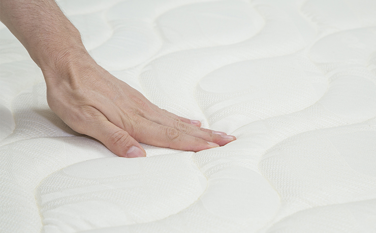 Image of a hand pressing down on a mattress.