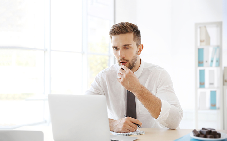Image of a man snacking on chocolate at work.