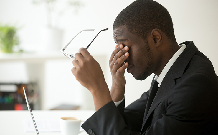 Image of a man taking off his glasses and rubbing tired eyes.