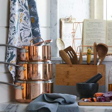 A kitchen sideboard with copper pots stacked on the side.