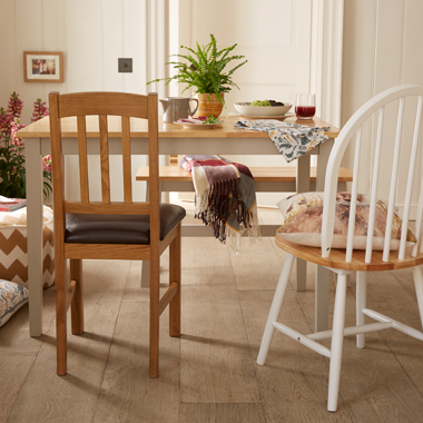 A dining room scene with two-tone table, surrounded by a mix and match of chairs and benches.