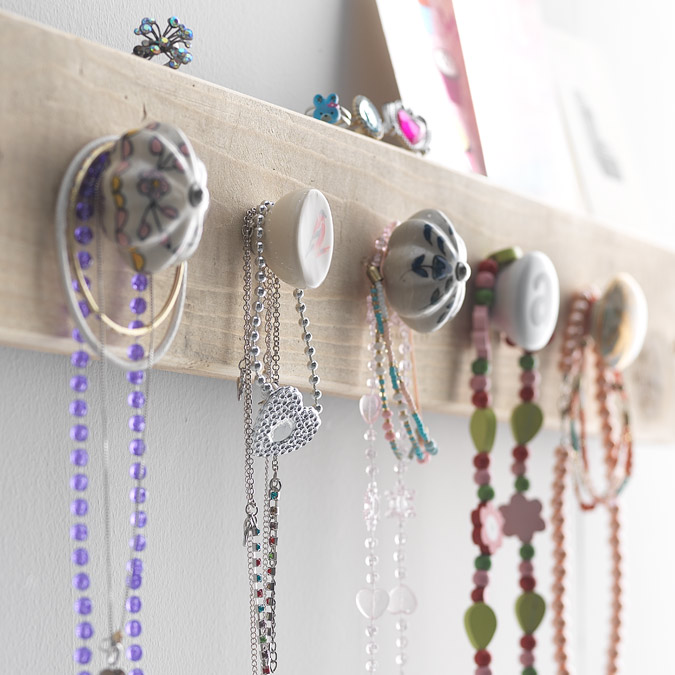 Wooden board with knobs for hanging children's necklaces and jewellery.