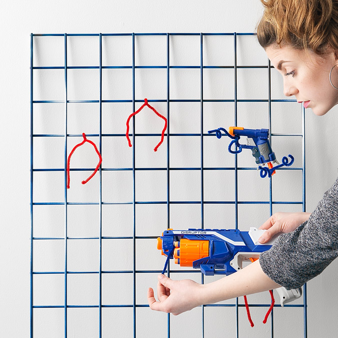 A woman adding toys and water guns to the wire rack with plastic ties.