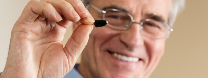 Man holding small hearing aid.
