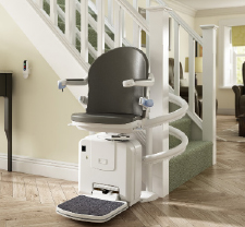 Age UK stairlift located at end of curved bannister.