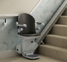 Age UK stairlift fixed at left hand size, bottom of flight of stairs.