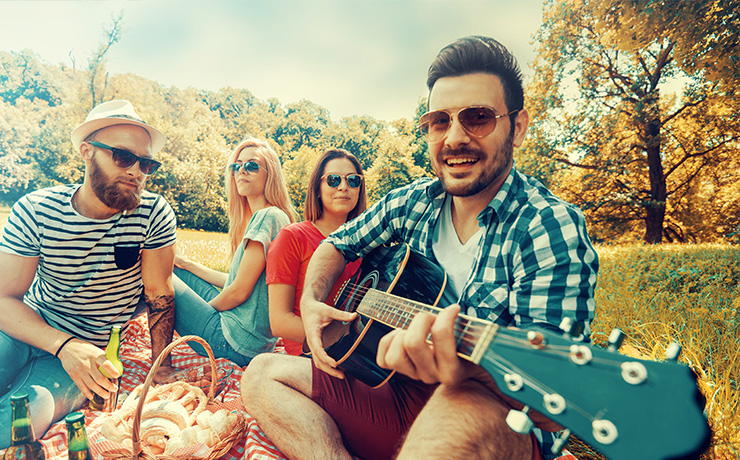 Image of a man playing a guitar to a group of friends