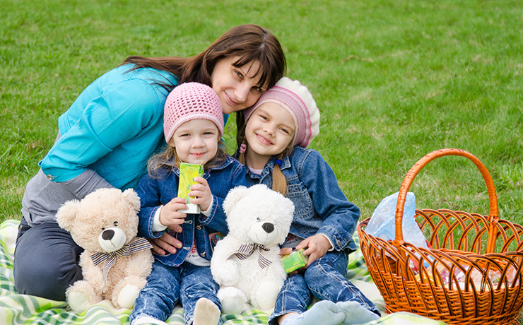 Image of a mum and two daughters enjoying a teddy bear's picnic