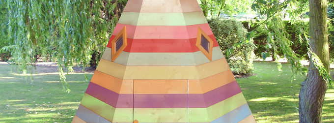 A wigwam playhouse painted in a rainbow effect.