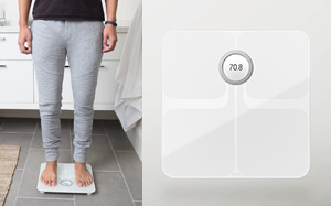 Image of a person standing on Fitbit Aria 2 scales from the waist down on the left and a cutout image of the Fitbit Aria scales on the right.