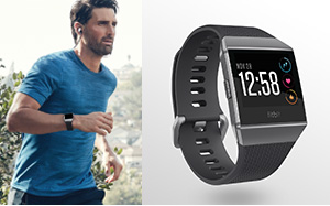Image of a woman running through grassland dressed in black wearing a Fitbit Ionic and a cutout image of a Fitbit Ionic smartwatch on the right.