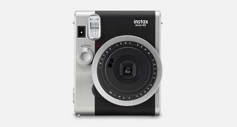Cut-out image of an instax Mini 90 instant camera on a grey background.