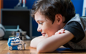 Lifestyle image of the Anki Cozmo robot looking at a boy.