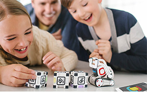 Lifestyle image of the Anki Cozmo robot playing with a boy and girl.