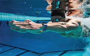 Image of a man diving through the water in a swimming pool wearing a Fitbit Ionic.