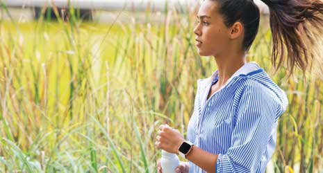 Image of a girl in blue hoody running with a Fitbit Versa smartwatch on her wrist.