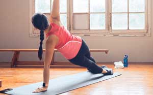 Image of a lady doing side plank in a gym.