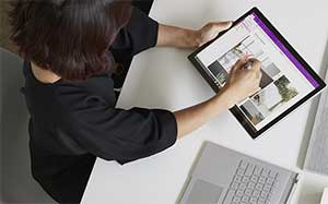 Image of a woan standing working on a Microsoft Surface in tablet form.